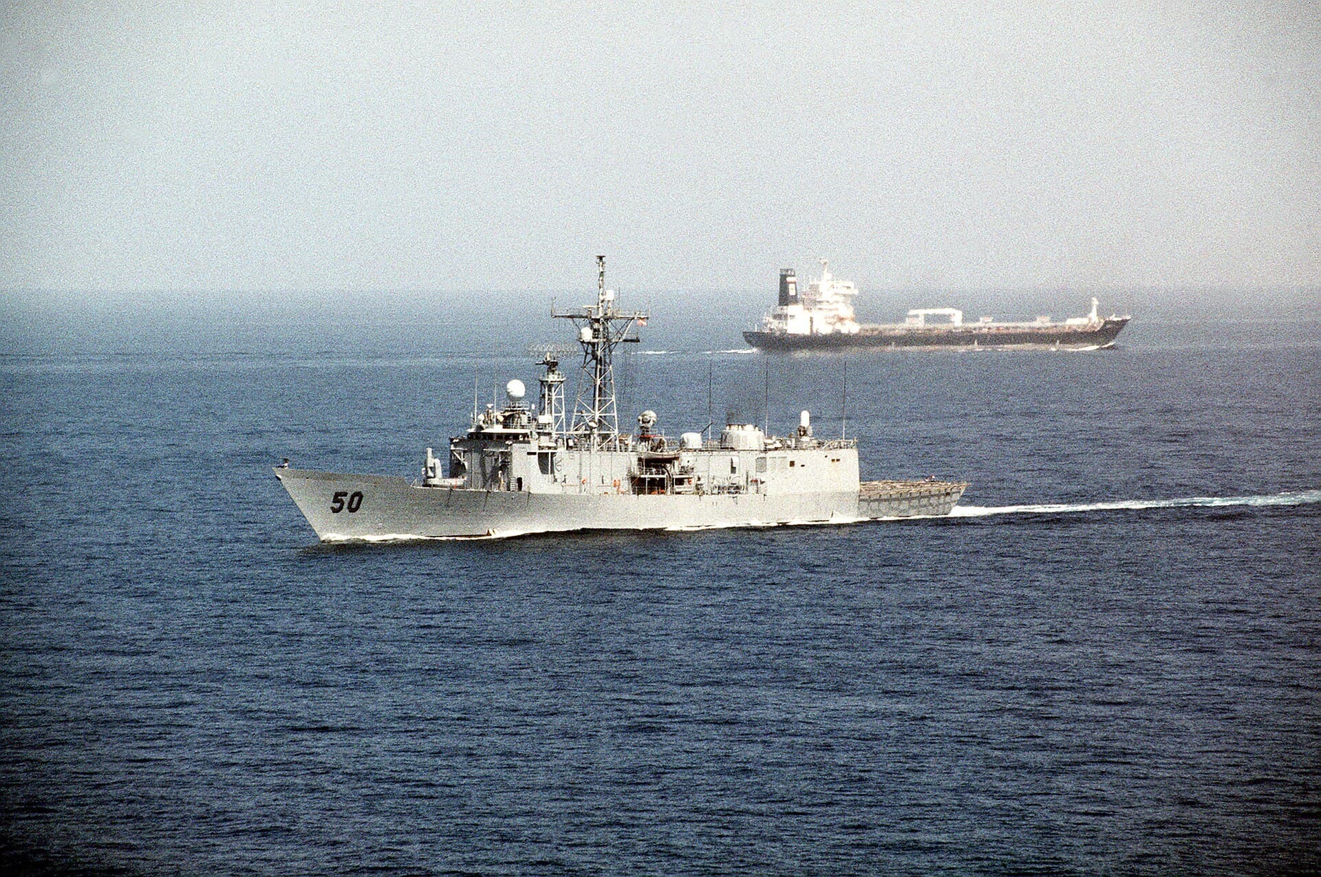 USS Taylor guided missile frigate passing an oil tanker through the Strait of Hormuz
